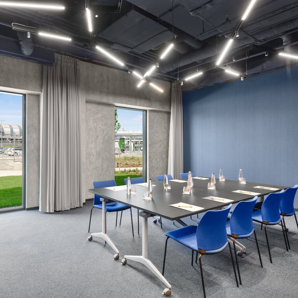 Meeting tables in a U-shape with blue and white chairs.