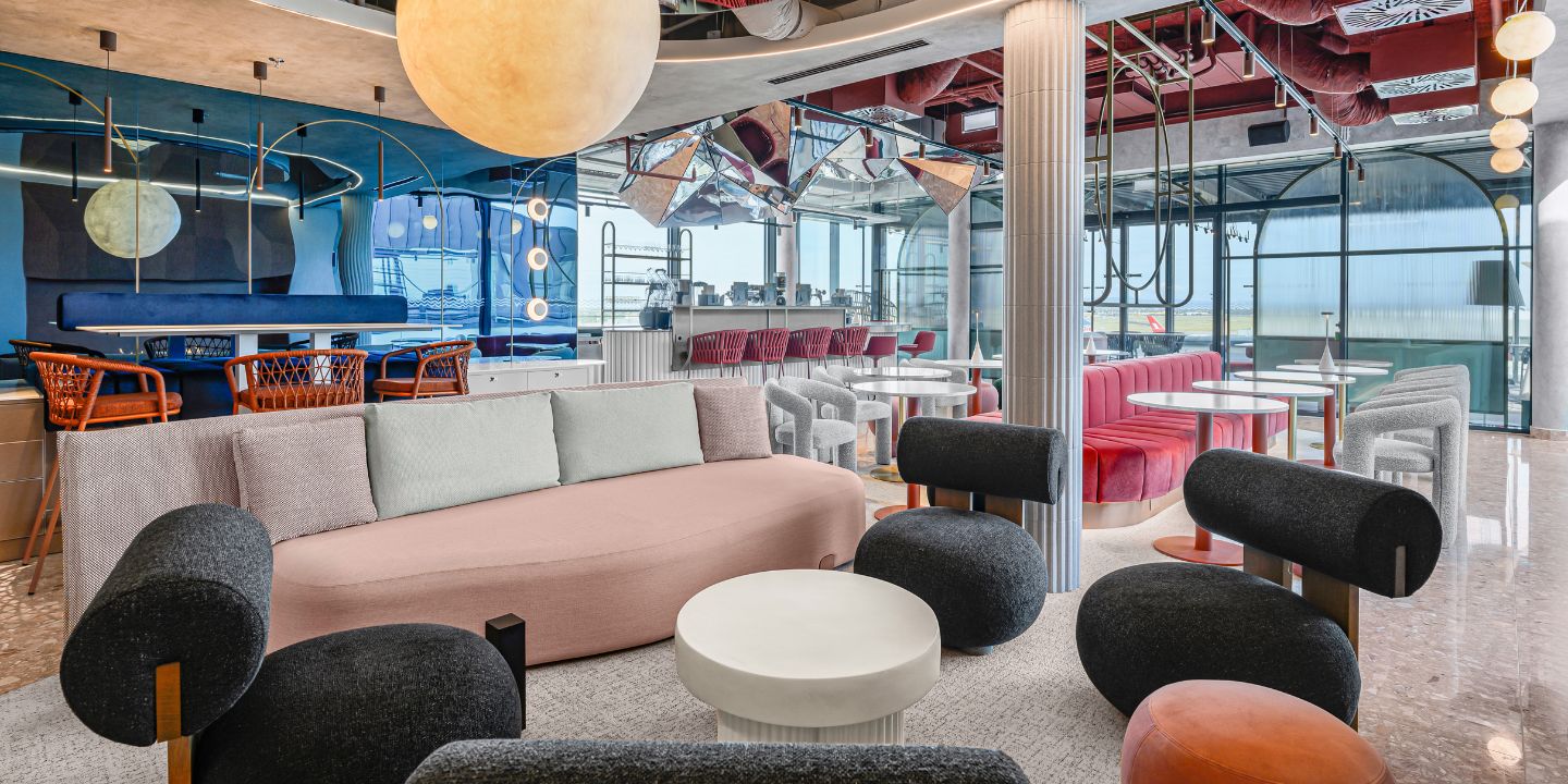 Sky bar lounge with colourful seating, round tables and large windows.