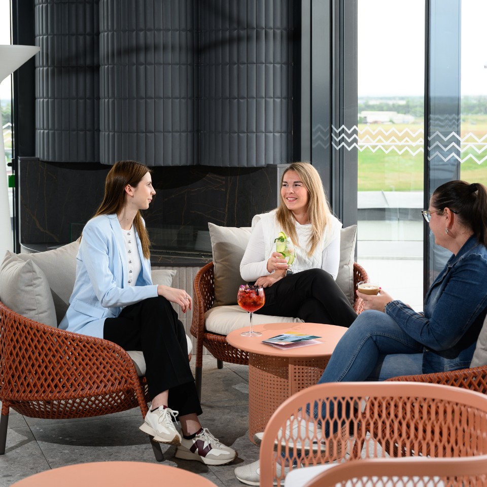 Three people talk over drinks in a lounge.