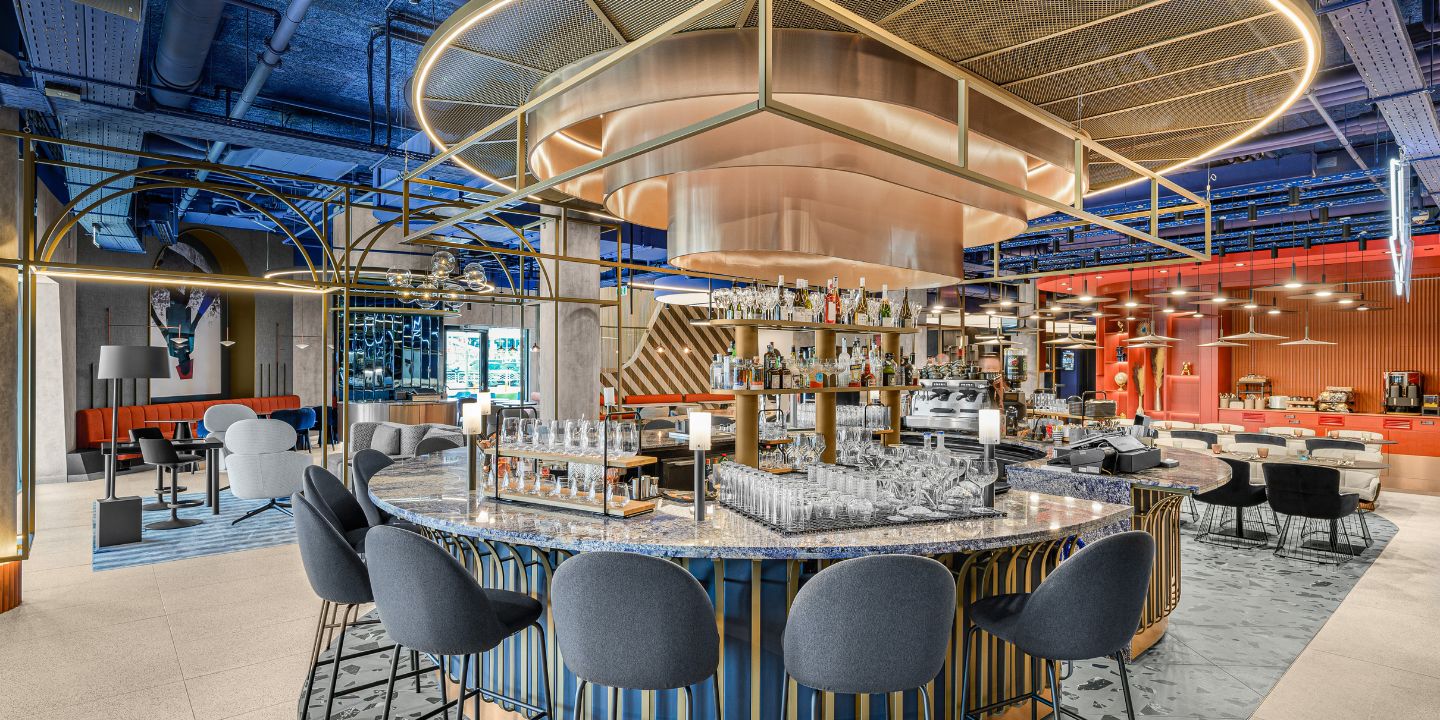 Circular bar with blue stools beneath sculptural lighting.