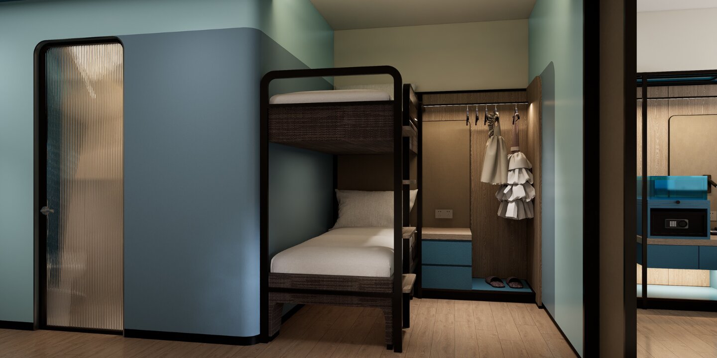 Compact hotel family room with an integrated wooden bunk bed, blue drawer chest, open wardrobe rack, and a ribbed glass sliding door.