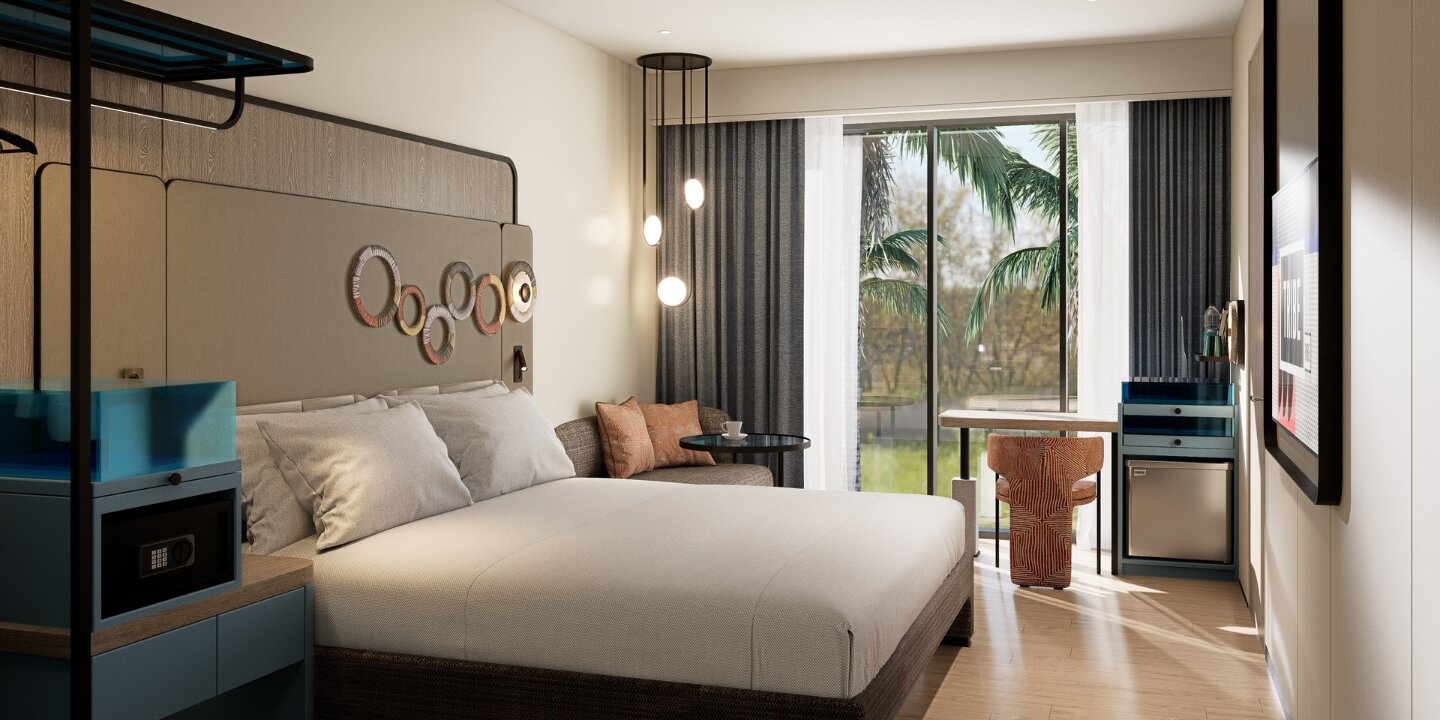 Bright hotel bedroom with a king-sized bed, wall-mounted ring art, cozy seating corner, and sliding glass doors opening to tropical palm trees.