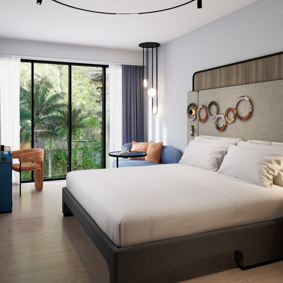 Bright hotel room with a king-size bed, abstract wall-mounted ring art, a blue sofa seating corner, and large glass windows facing palm trees.