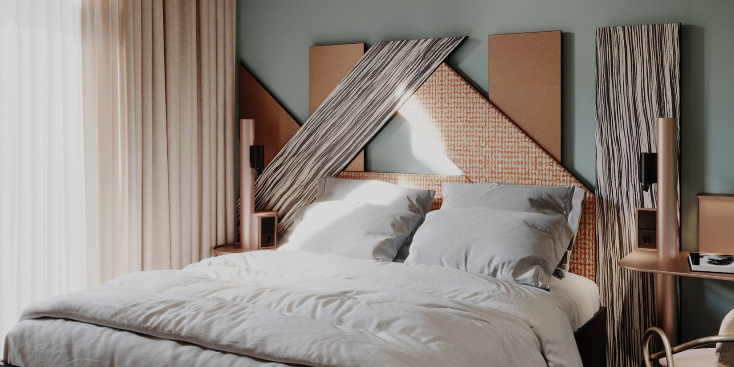 A double bed in a boutique hotel room featuring a dramatic, custom-designed geometric headboard with black-and-white stripes and woven textures against a sage green wall.