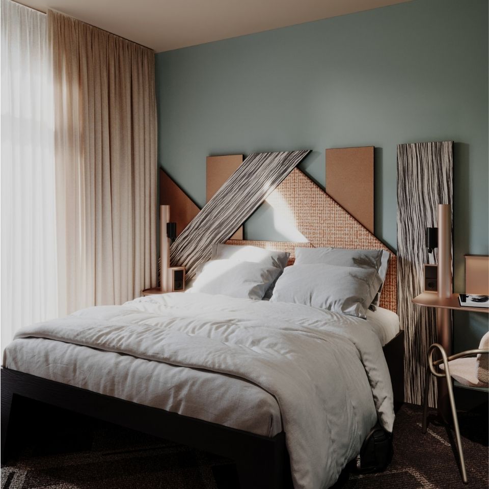 A double bed with white bedding and a geometric headboard.