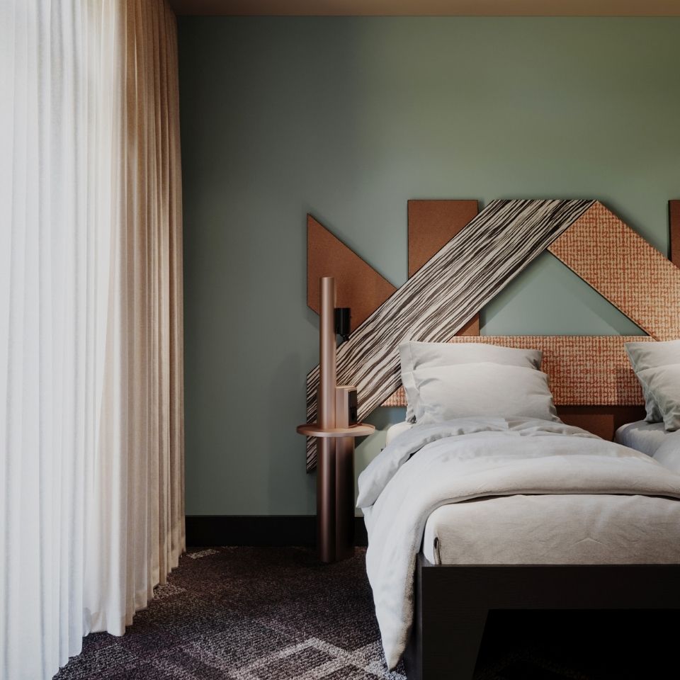 Cozy single bed setup in a modern hotel room, showcasing a bold geometric wooden headboard against a muted sage green wall beside flowing neutral drapes.