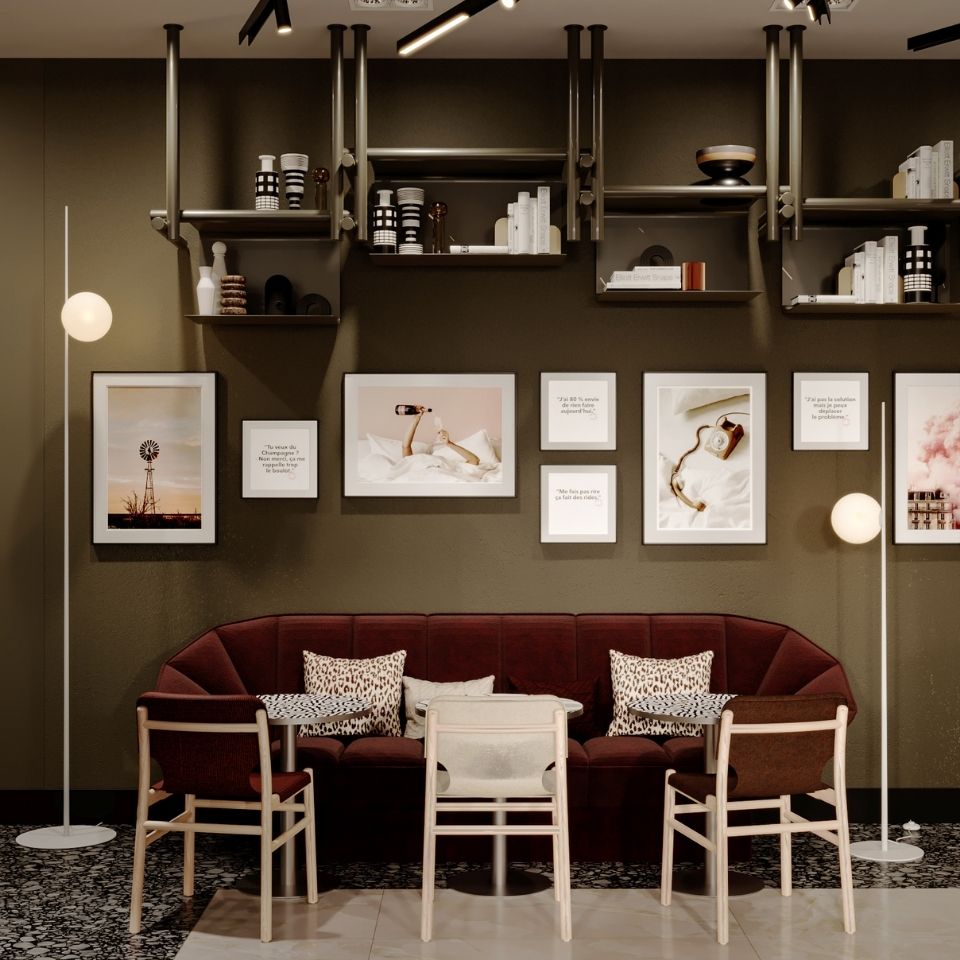 Chic hotel lounge nook featuring a curved burgundy velvet banquette, leopard-print throw pillows, circular bistro tables, and a gallery wall under industrial shelving.