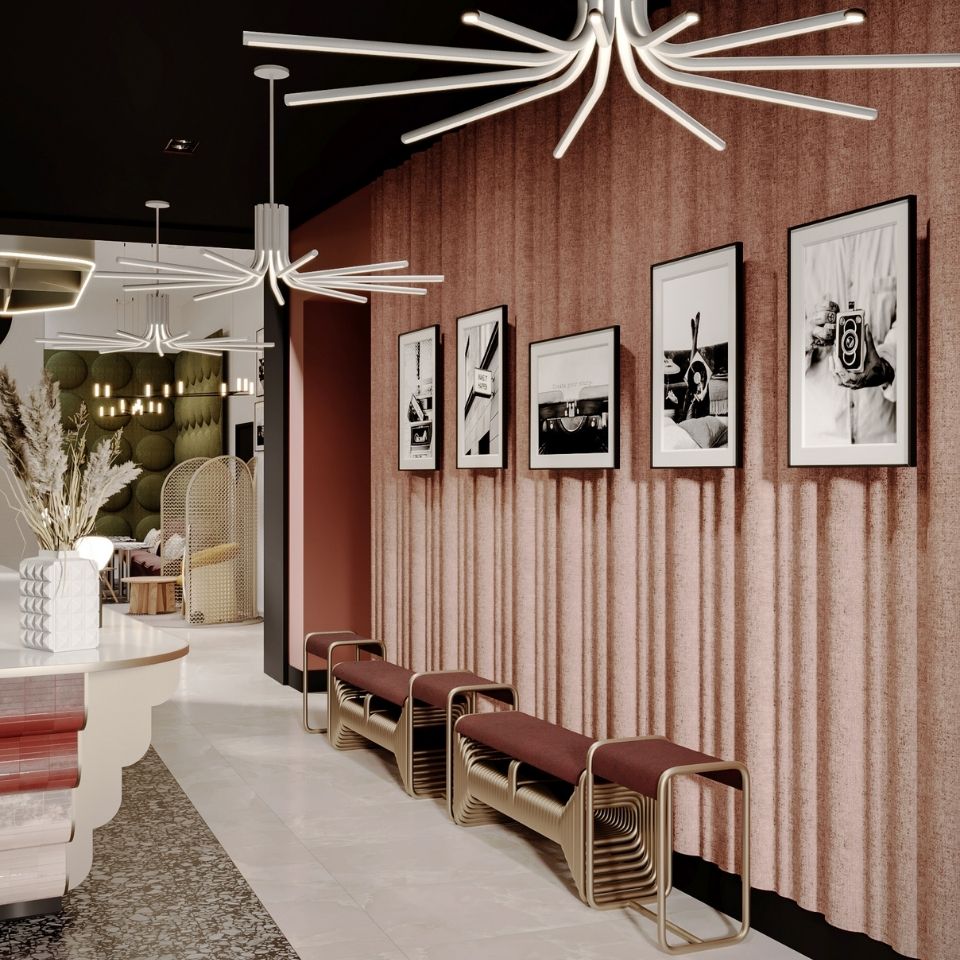Elegant hotel hallway featuring curved golden benches, a textured dusty-pink curtain wall, and a curated gallery of framed black-and-white photographs.