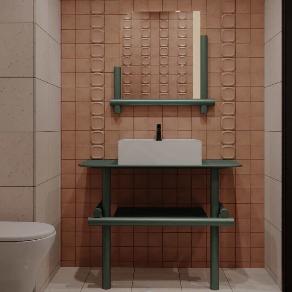 Modern hotel bathroom featuring coral pink square tiles, a forest green tubular metal vanity with a white vessel sink, and a matching green-framed mirror.