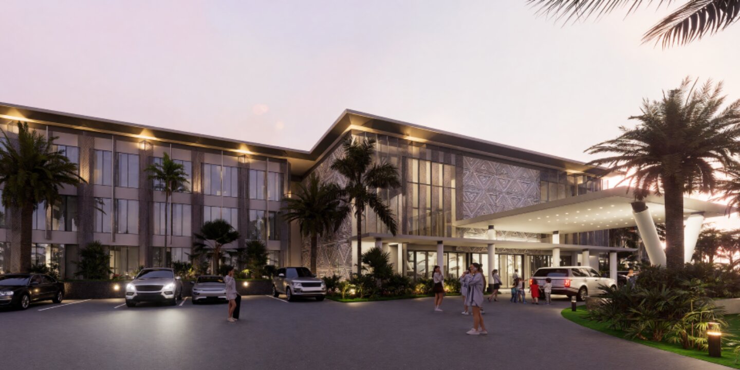 Modern hotel entrance at dusk with cars parked, palm trees, and people walking around the driveway.