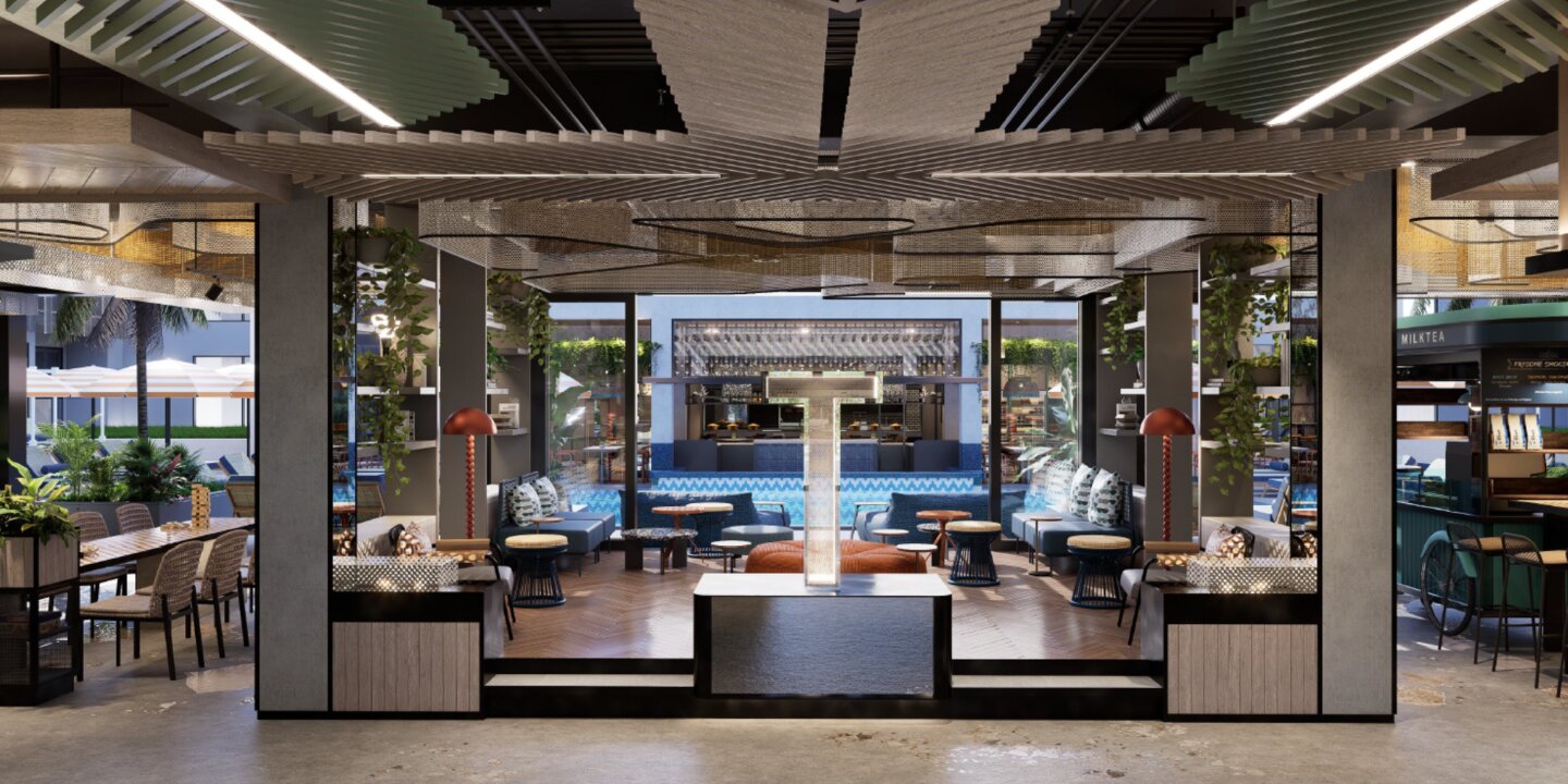 Modern indoor lounge area with seating, tables, plants, a central illuminated sculpture, and views of an outdoor pool and café.