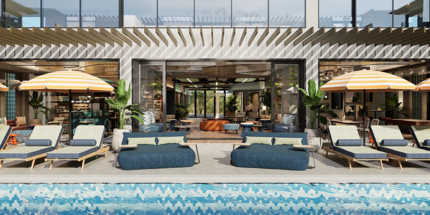Modern outdoor pool area with cushioned lounge chairs, yellow-striped umbrellas, blue sofas, and a spacious indoor lounge visible through glass doors.