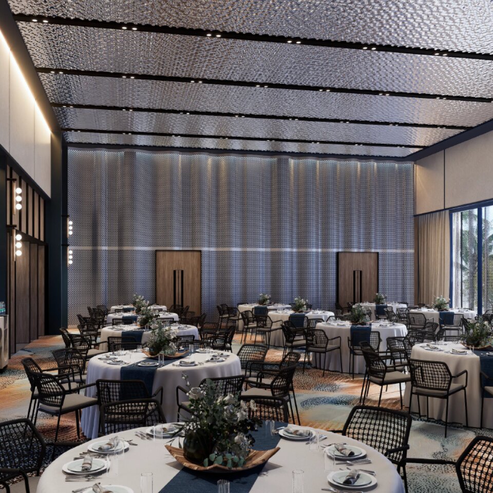 Elegant hotel ballroom set up with round banquet tables, white tablecloths, navy blue runners, floral centerpieces, and modern black chairs.