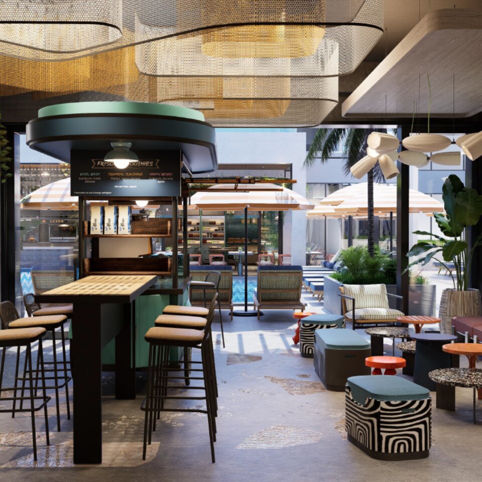 Vibrant hotel juice bar with tall stools, patterned floor poufs, and a smoothie menu board opening directly onto a sunny pool deck.
