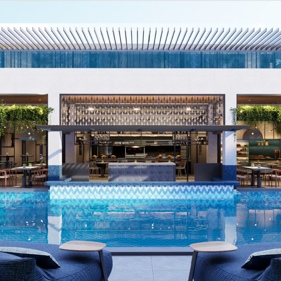 Modern resort swimming pool looking towards an open-air poolside bar and restaurant with hanging green plants.